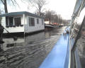 typical houseboat -- This shows a typical houseboat moored to the canal bulkheads. They range from trailor houses on floats, to some pretty ornate places. It's not clear how they take care of the grey and black water - but there's apparently a solution since the canals didn't have any floating debris.