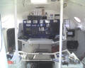 A view from immediatly inside the main cabin, looking at the chart table / navigation instruments. The seat is actually the cover for the engine. There are no living accomodations in the hull. Note the video camera in the upper right of the nav station.